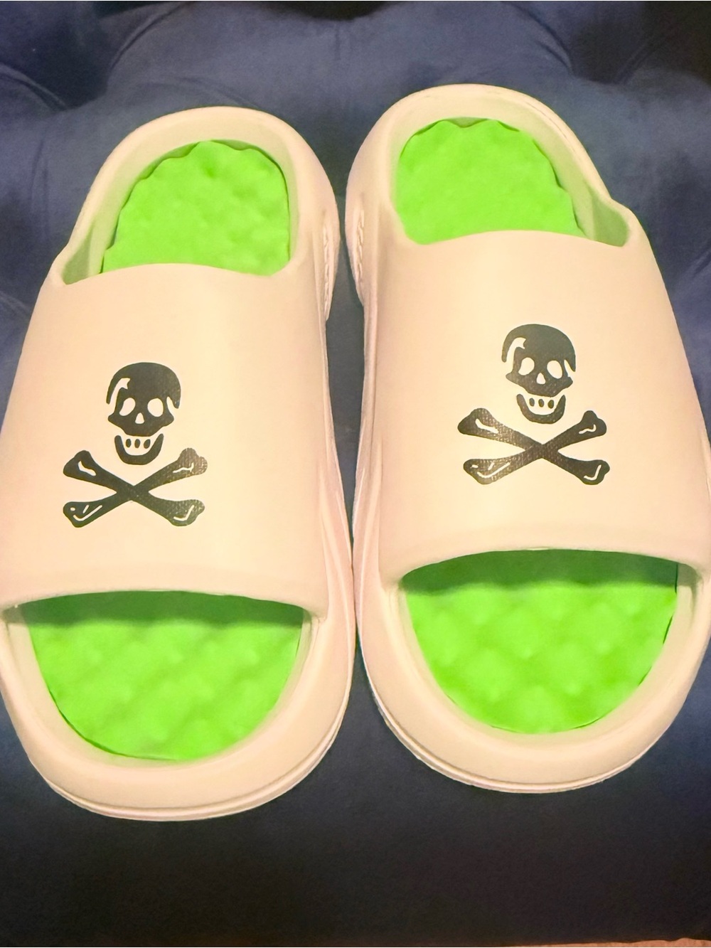 Men’s white EVA skull slides feature a vibrant green massage footbed